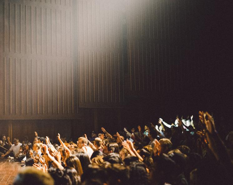 Lecture hall, hands raised. 